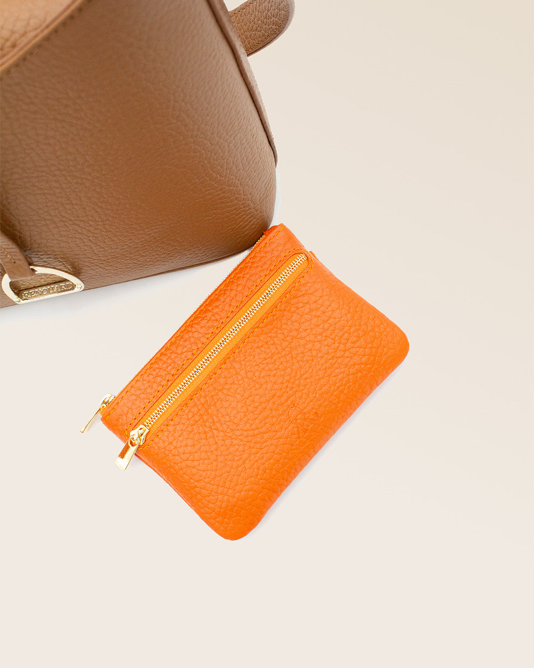 Notre porte-monnaie Capucine en cuir façon vigogne orange vu de face en studio.