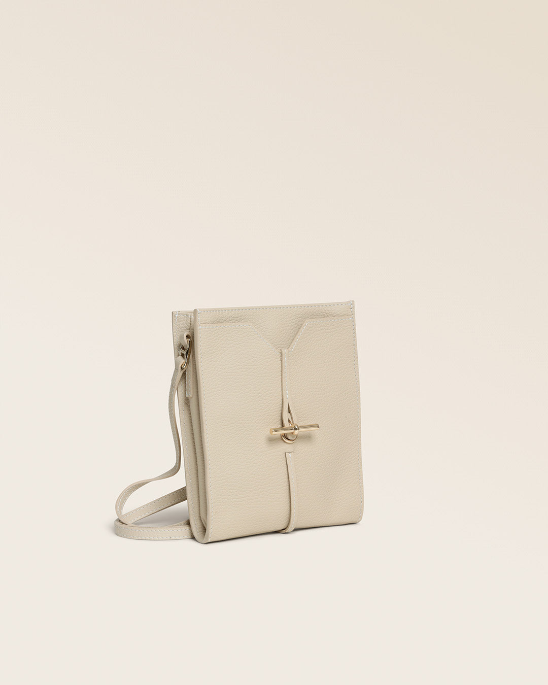 Notre pochette Aglaé Renouard en cuir façon vigogne crème, vue de quart en studio.