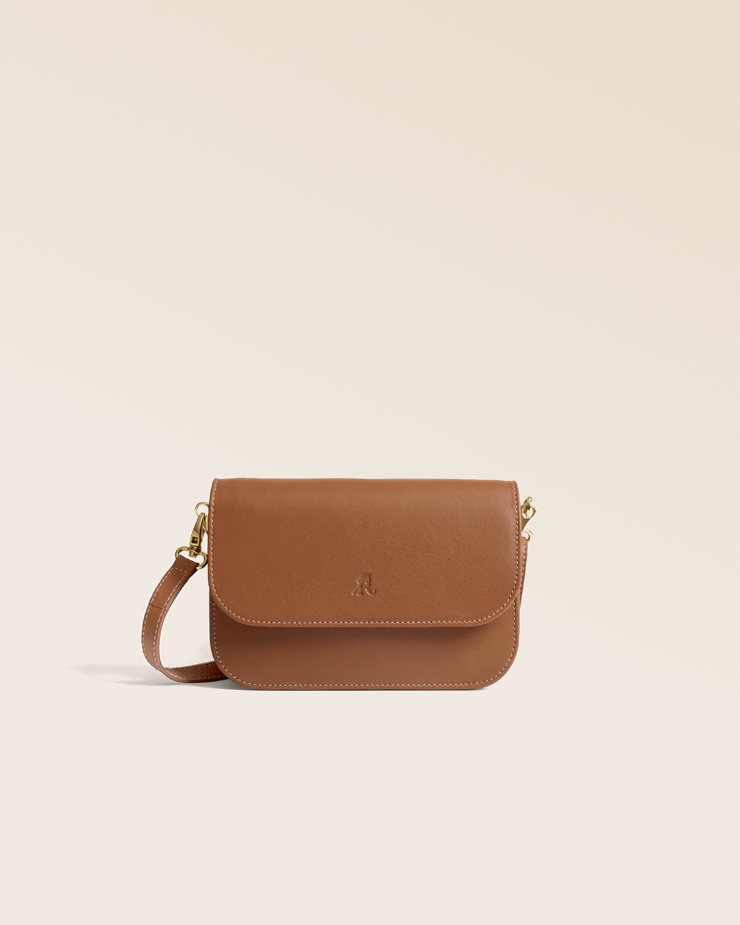 La pochette Coralie Renouard en cuir lisse camel et accessoires dorés, avec sa bandoulière amovible, vue de face en studio.
