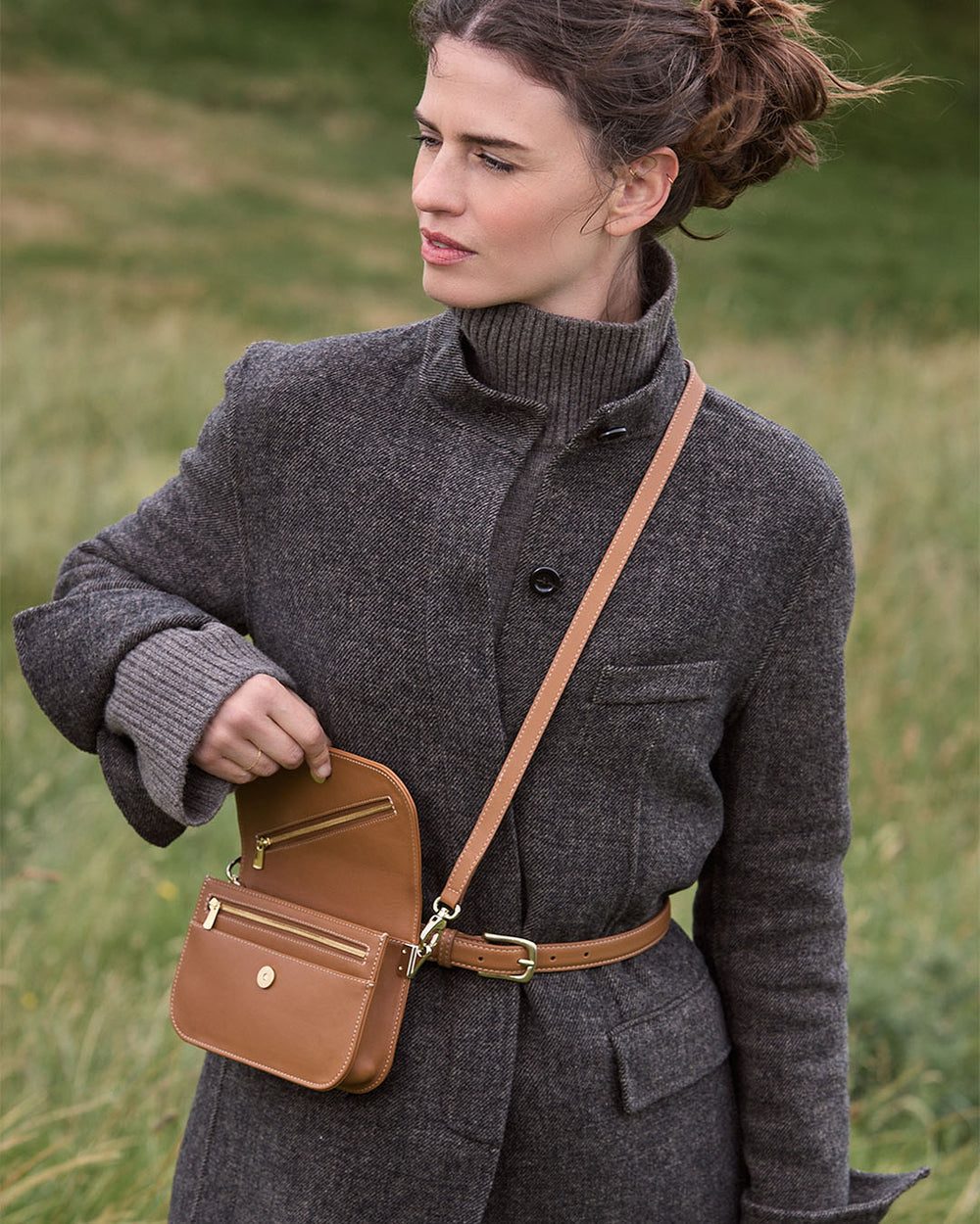 La pochette Coralie Renouard en cuir lisse camel et accessoires dorés, avec sa bandoulière amovible, vue portée par notre mannequin. 