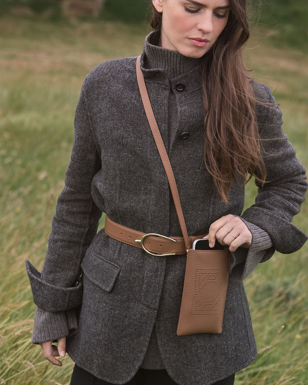 La pochette téléphone Étrivière en cuir façon vigogne fauve vue portée par notre mannequin. 