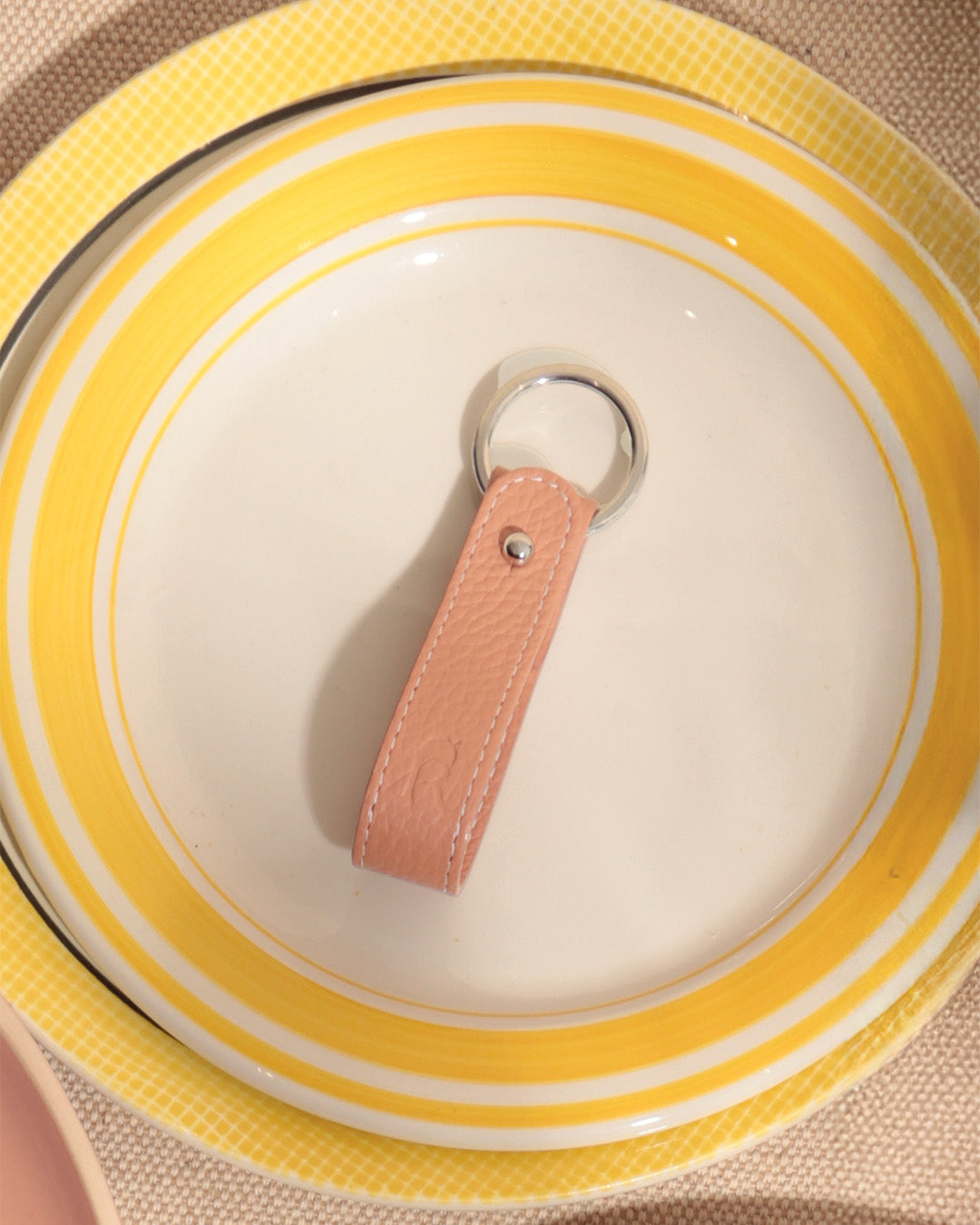 Notre porte-clés Léon Renouard en cuir façon vigogne pêche, vu de face en ambiance.