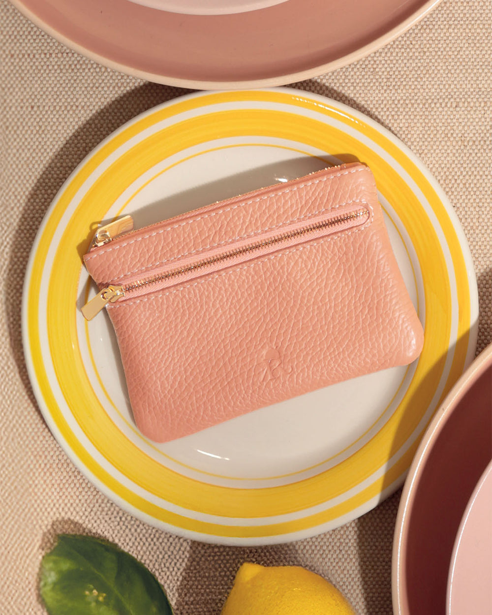 Notre porte-monnaie Capucine Renouard en cuir façon vigogne pêche, vu de face en ambiance.