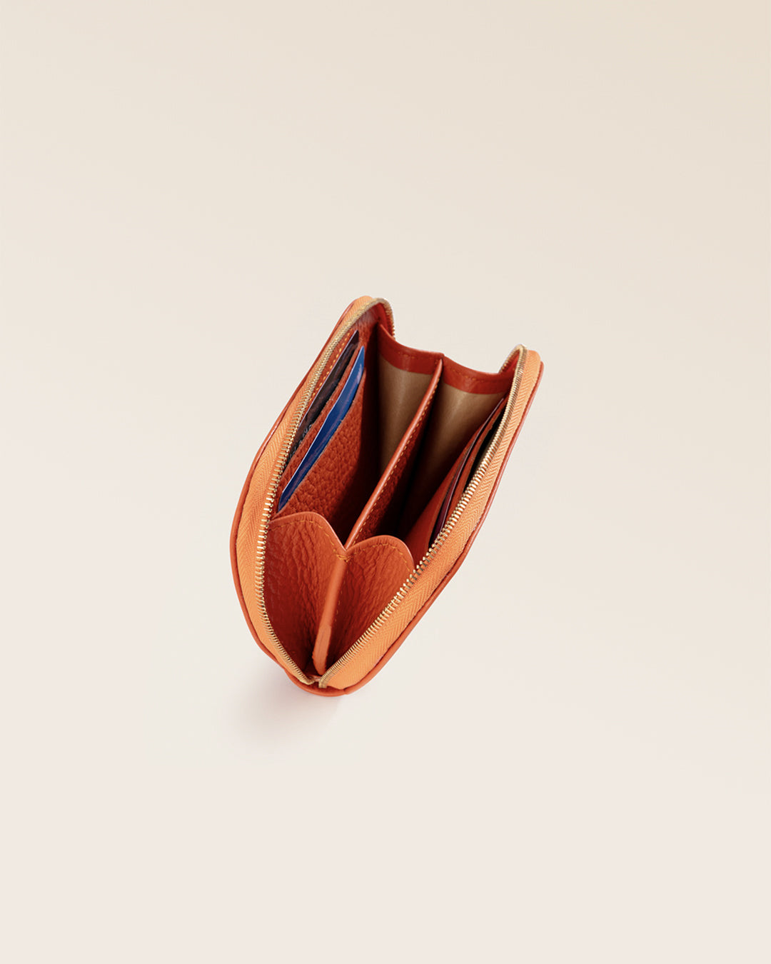 Notre porte-monnaie Galop Renouard, en cuir façon vigogne orange, vu de l'intérieur en studio.