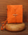 Notre pochette Aglaé Renouard en cuir façon vigogne orange, vue de face en ambiance.