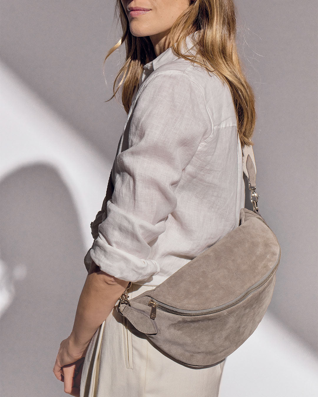 Notre sac Batz Renouard en cuir veau velours taupe et sa bandoulière coton craie, vu porté par notre mannequin.