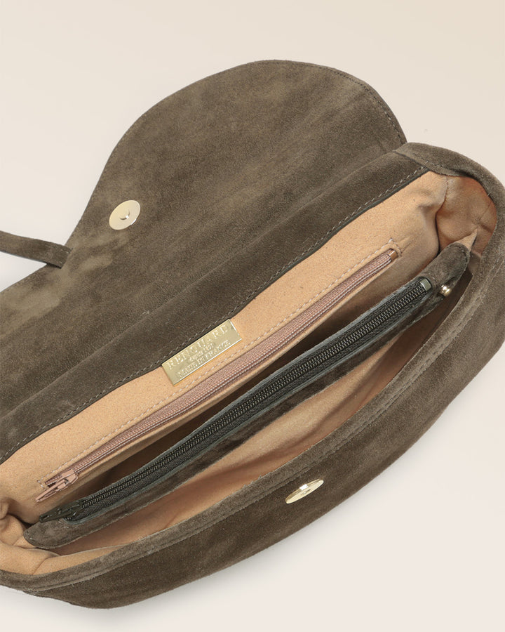 Notre sac Cavalerie Renouard en cuir veau velours truffe avec sa bandoulière en coton, vu ouvert du dessus en studio. 