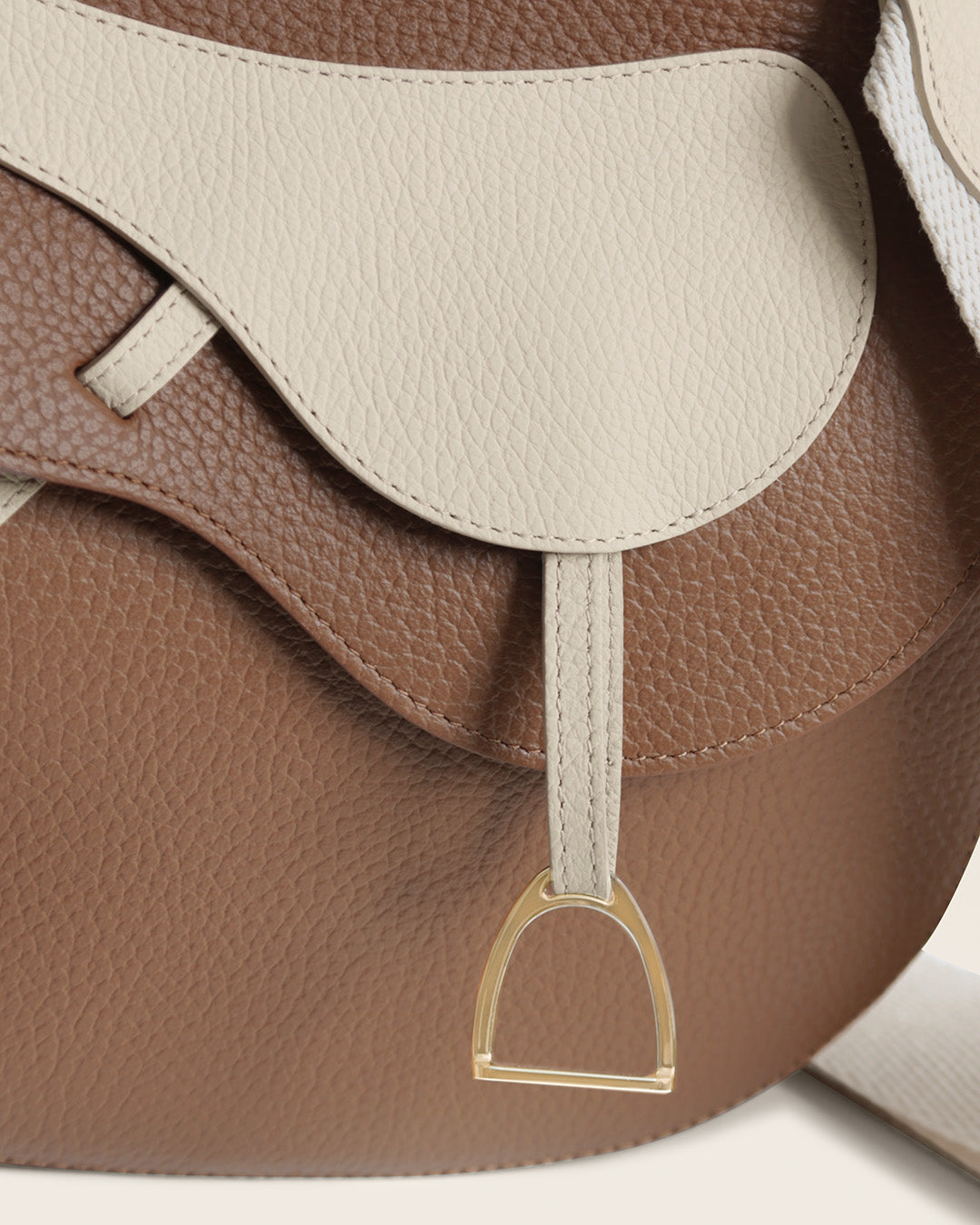 Notre sac Cavalerie Renouard en cuir façon vigogne fauve et crème, avec sa bandoulière coton craie, vu de près en studio.