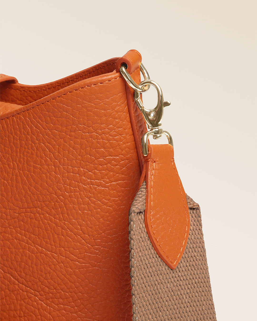 Notre sac Cob Renouard dans sa version Mini modèle, cuir façon vigogne orange et bandoulière coton ; vu de près en studio.