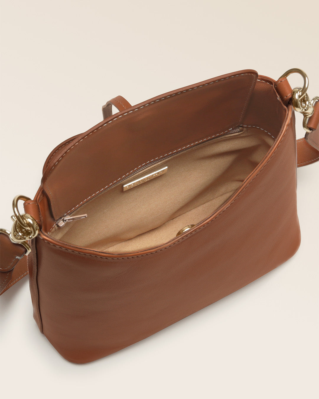 Notre sac Cob Renouard dans sa version Mini modèle, en cuir vintage camel et bandoulière cuir ; vu ouvert du dessus en studio.
