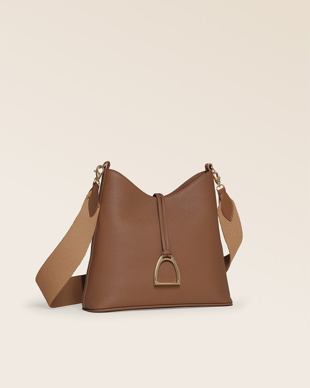 Notre sac Cob Renouard dans sa version Petit modèle, cuir façon vigogne fauve et bandoulière coton ; vu de quart en studio.