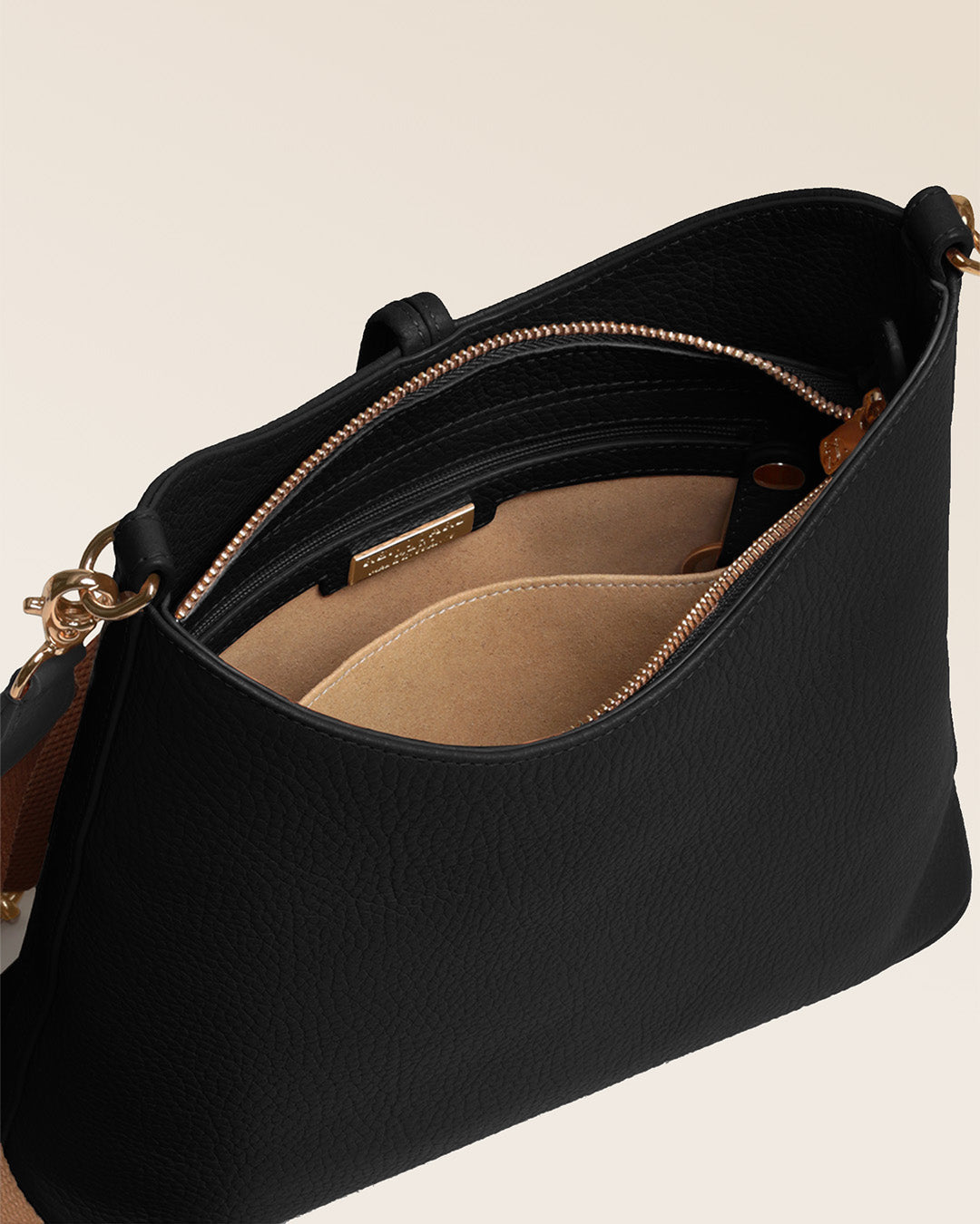 Notre sac Cob Renouard dans sa version Petit modèle, en cuir façon vigogne noir, accessoires dorés et bandoulière coton ; vu du dessus en studio.