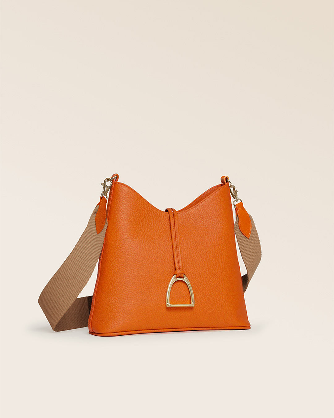 Notre sac Cob Renouard dans sa version Petit modèle, en cuir façon vigogne orange, accessoires dorés et bandoulière coton ; vu de quart en studio.