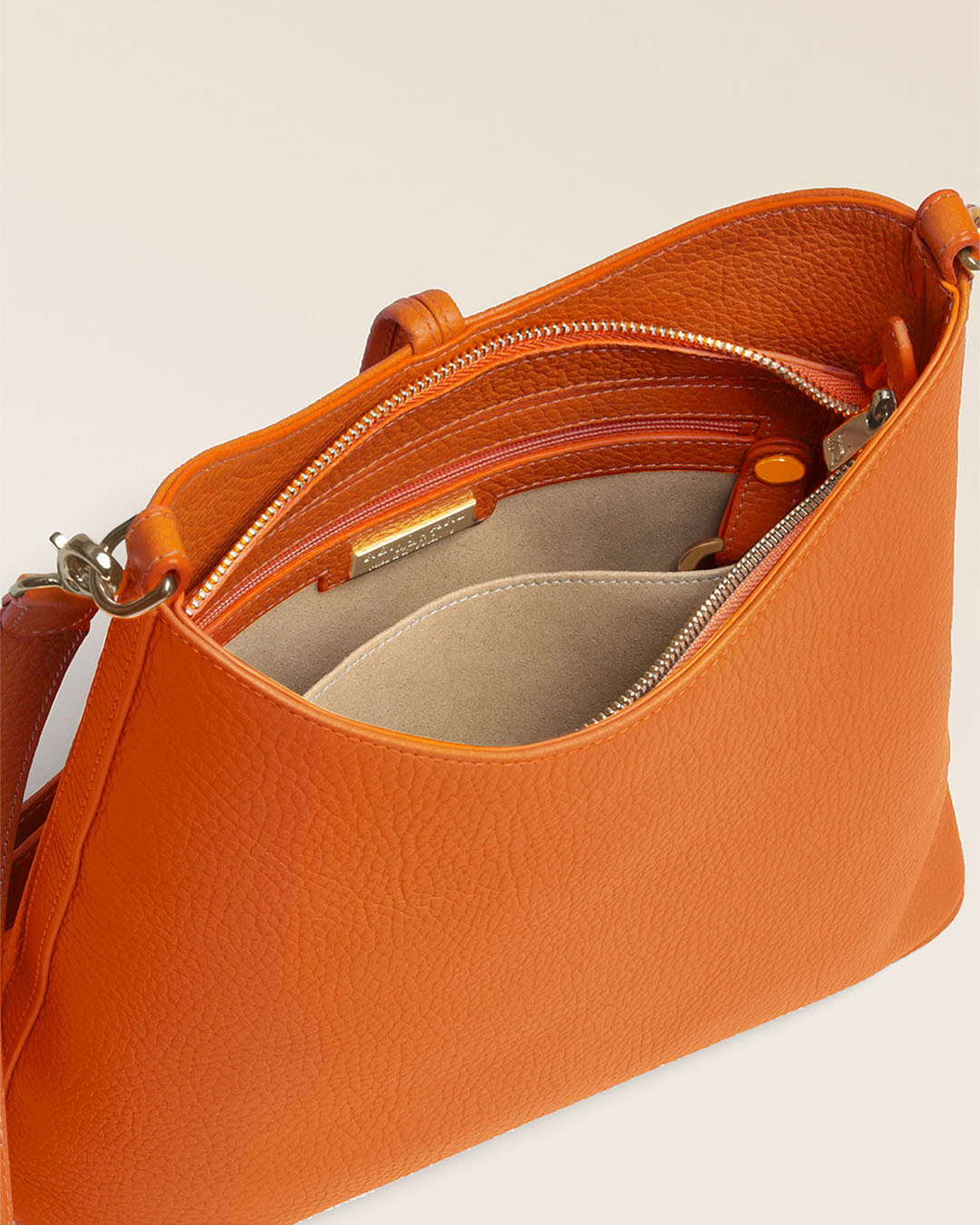 Notre sac Cob Renouard dans sa version Petit modèle, en cuir façon vigogne orange, accessoires dorés et bandoulière cuir ; vu du dessus en studio.