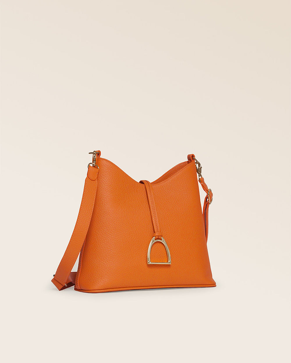 Notre sac Cob Renouard dans sa version Petit modèle, en cuir façon vigogne orange, accessoires dorés et bandoulière cuir ; vu de quart en studio.