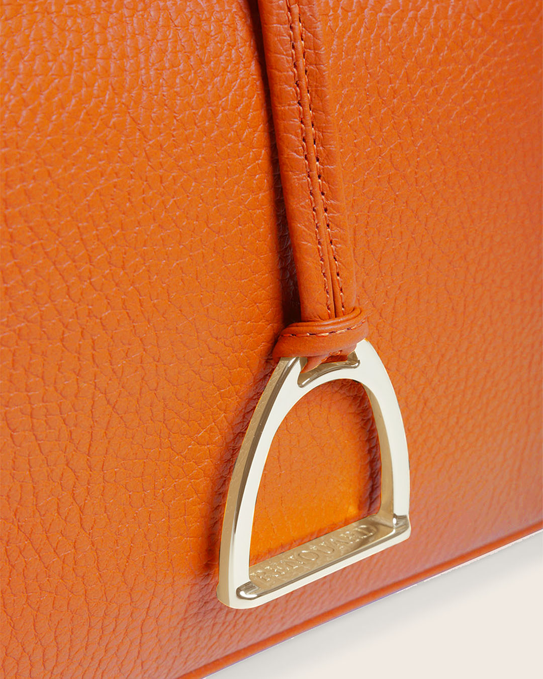 Notre sac Cob Renouard dans sa version Petit modèle, en cuir façon vigogne orange, accessoires dorés et bandoulière cuir ; vu de près en studio.