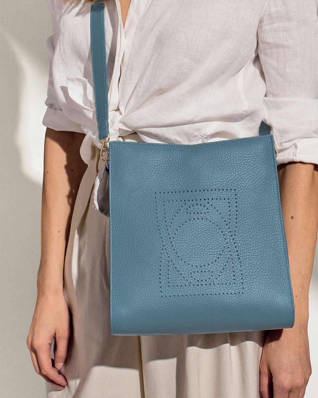 Notre sac Étrivière Renouard en cuir façon vigogne bleu cobalt, vu porté par notre mannequin.