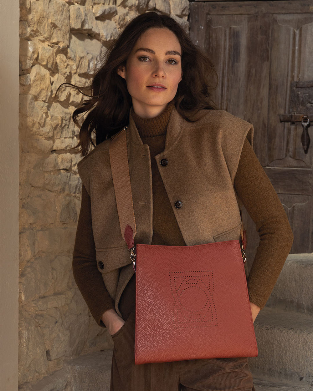 Notre sac Étrivière Renouard en cuir façon vigogne terracotta et bandoulière coton camel, vu porté par notre mannequin.