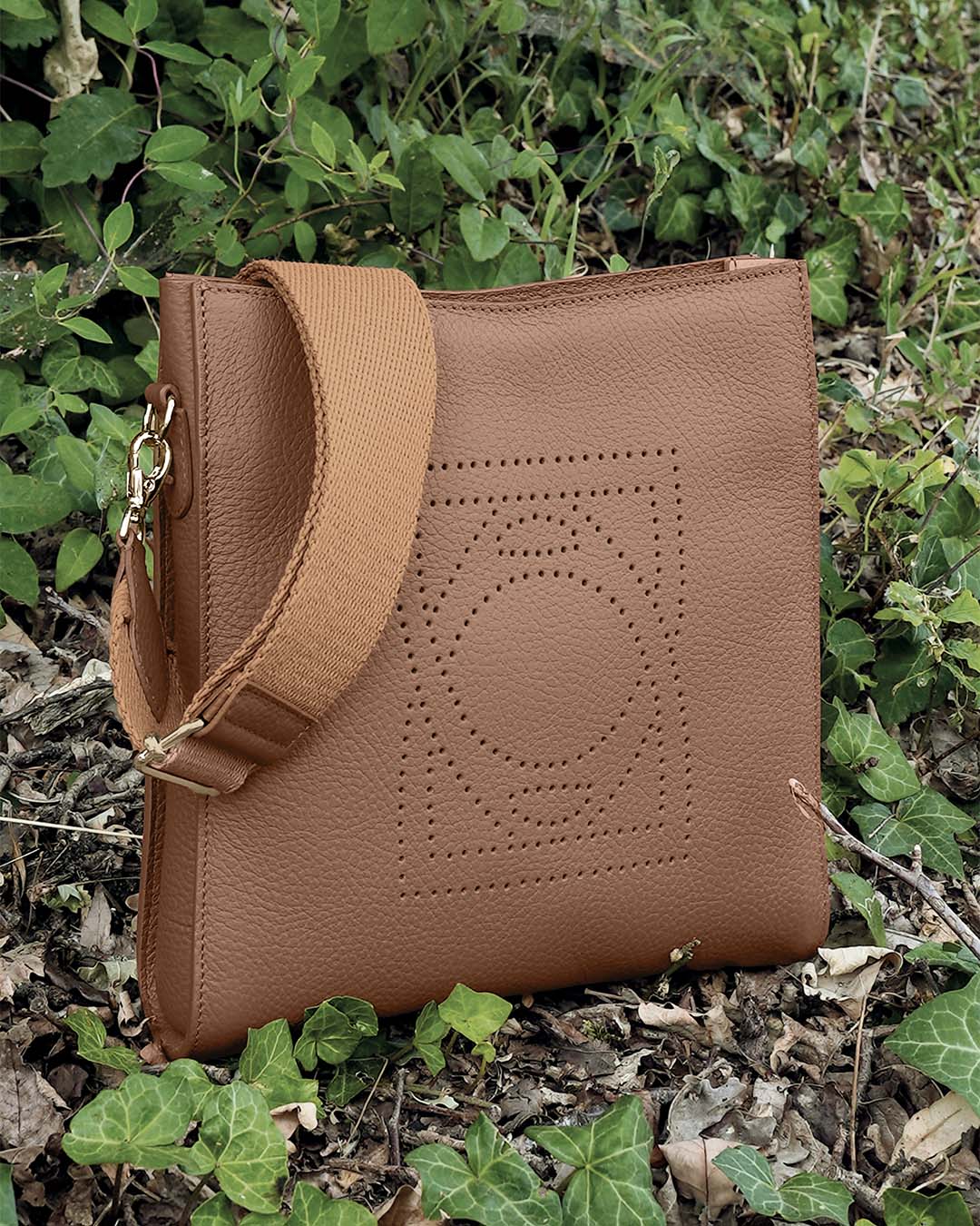 Le sac Mini Étrivière Renouard en cuir façon vigogne fauve et sa bandoulière coton camel, vu de quart en ambiance.