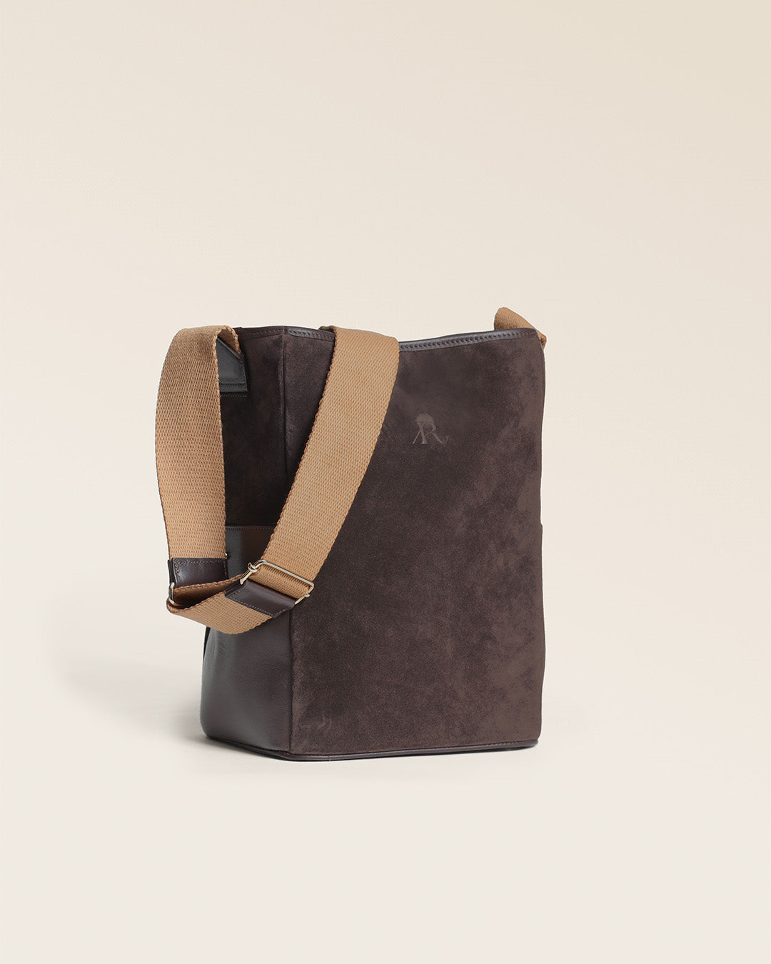 Le sac Gaspard Renouard en cuir veau velours espresso et lisse ébène, avec sa bandoulière coton camel, vu de quart en studio.