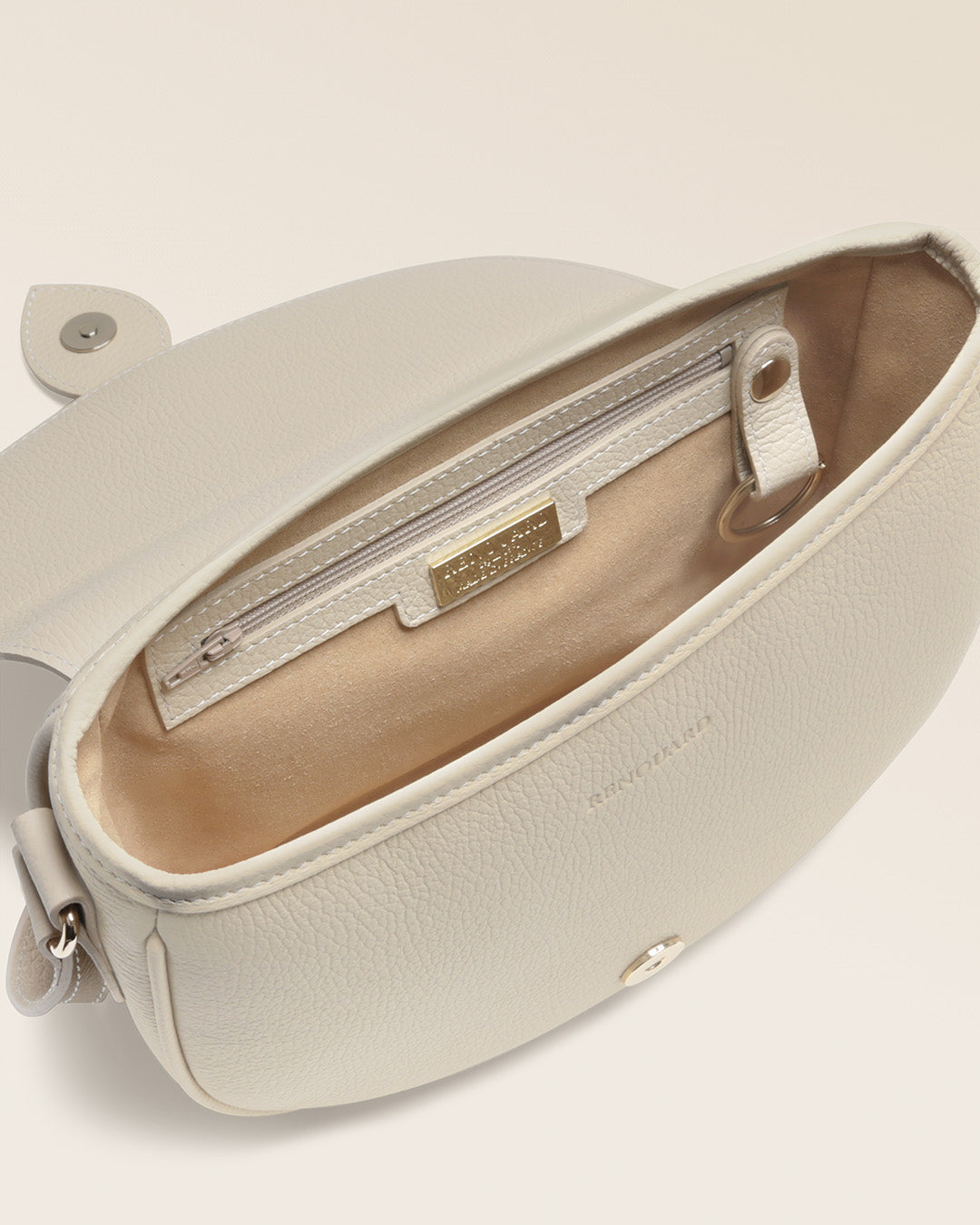 Notre sac gibecière Léa Renouard en cuir façon vigogne crème, vu de l'intérieur en studio.