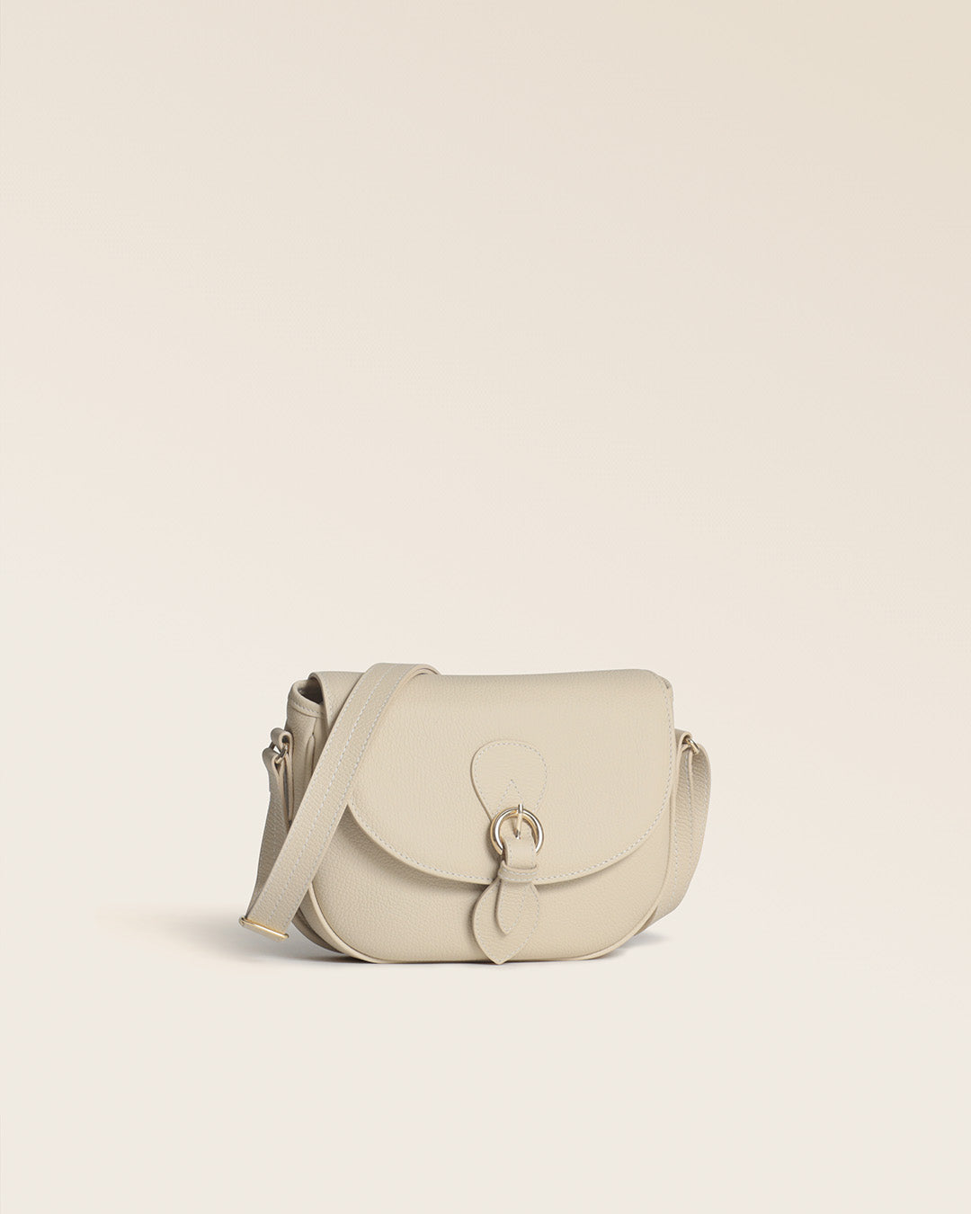 Notre sac gibecière Léa Renouard en cuir façon vigogne crème vu de quart en studio.