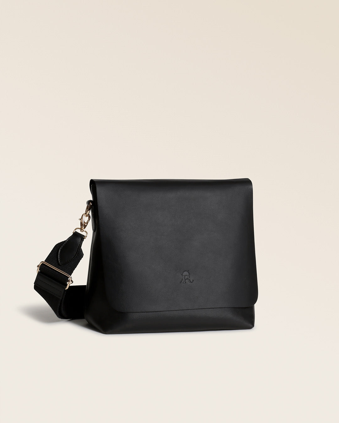 Notre sac Joy Renouard en cuir lisse noir avec sa bandoulière en coton noir, vu de quart en studio.