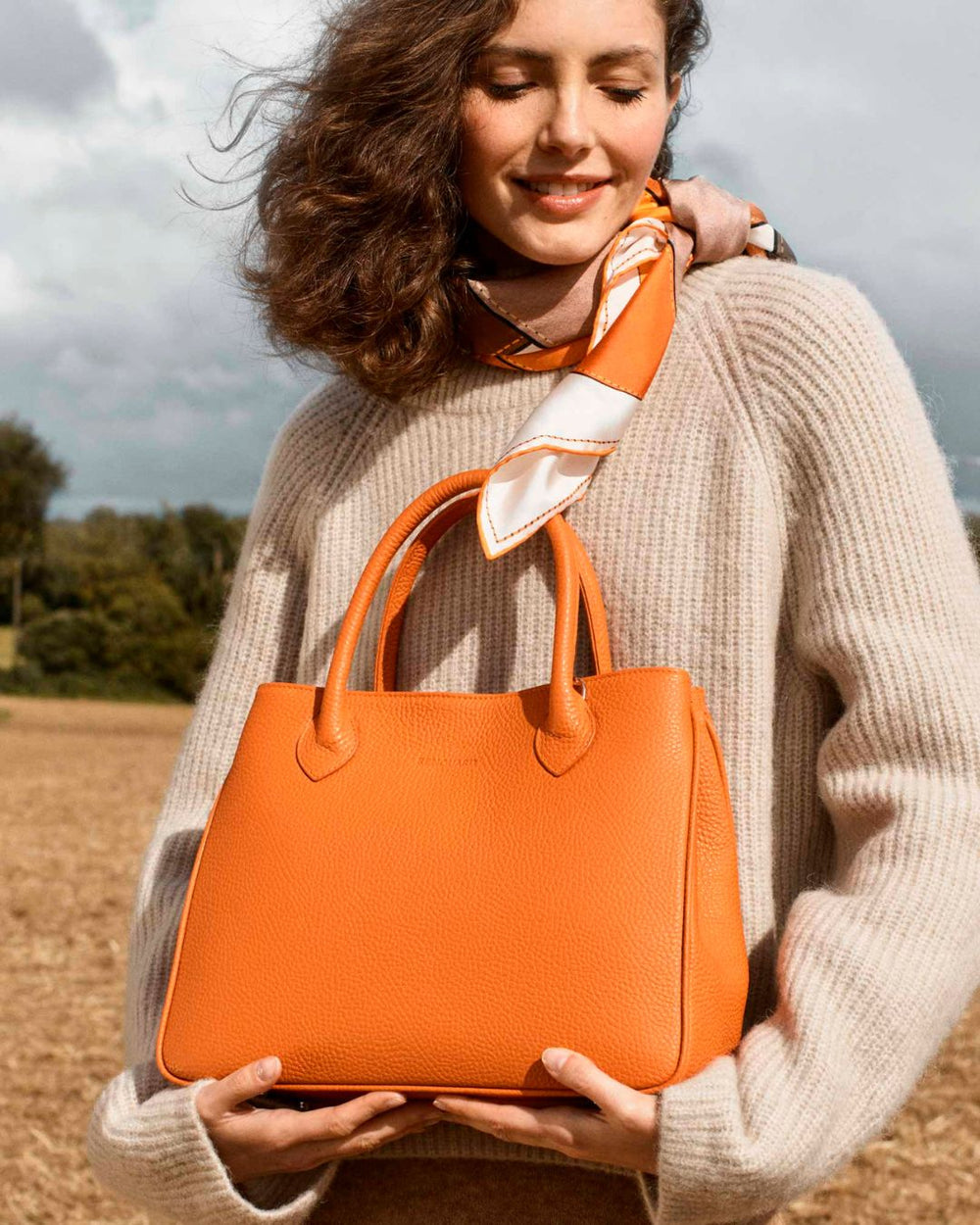 Notre sac Ker Balmoral en cuir façon vigogne orange vu porté par notre mannequin Léa Gouaux.