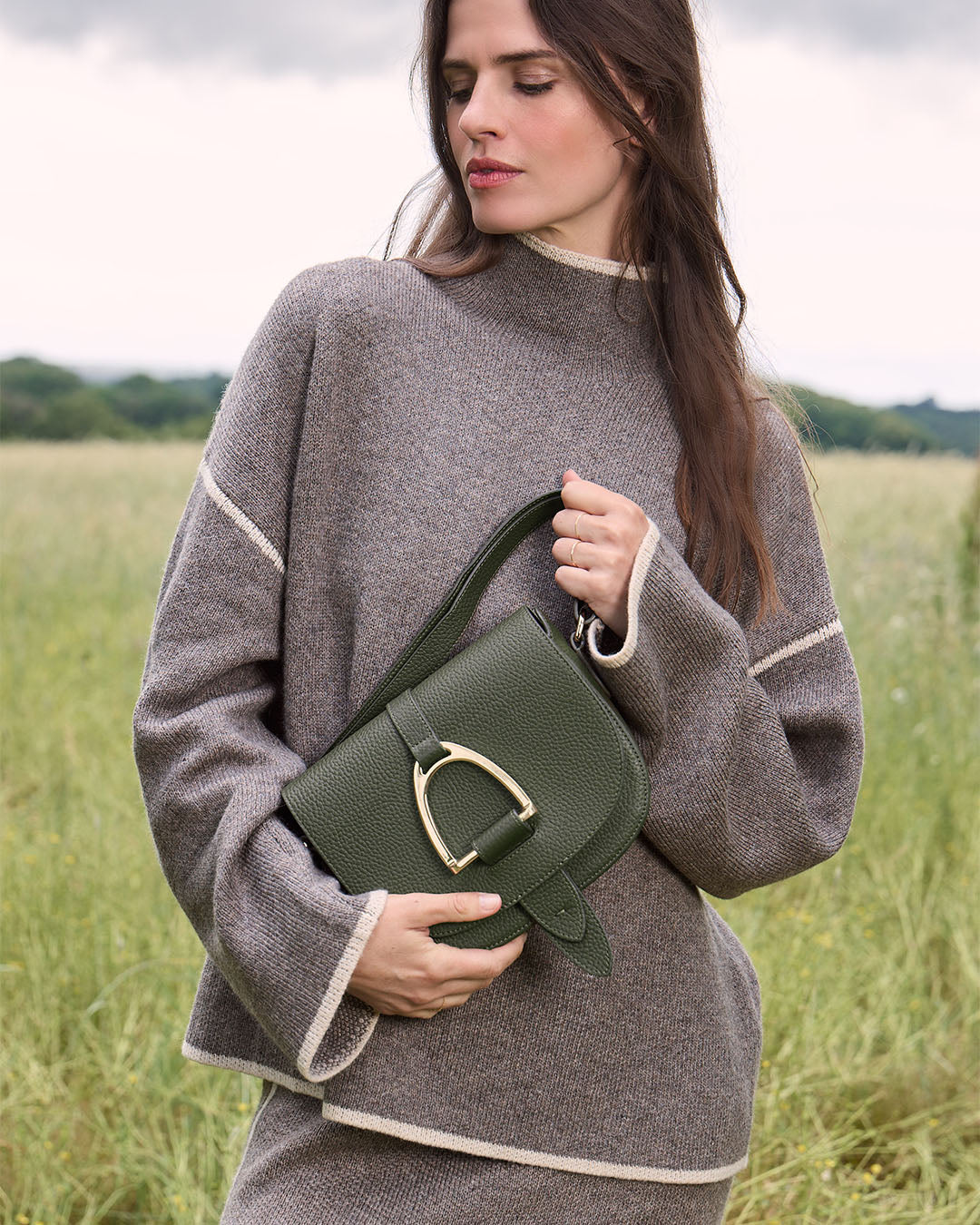 Le sac Licol Renouard en cuir façon vigogne kaki et son étrier doré pâle, vu porté par notre mannequin.