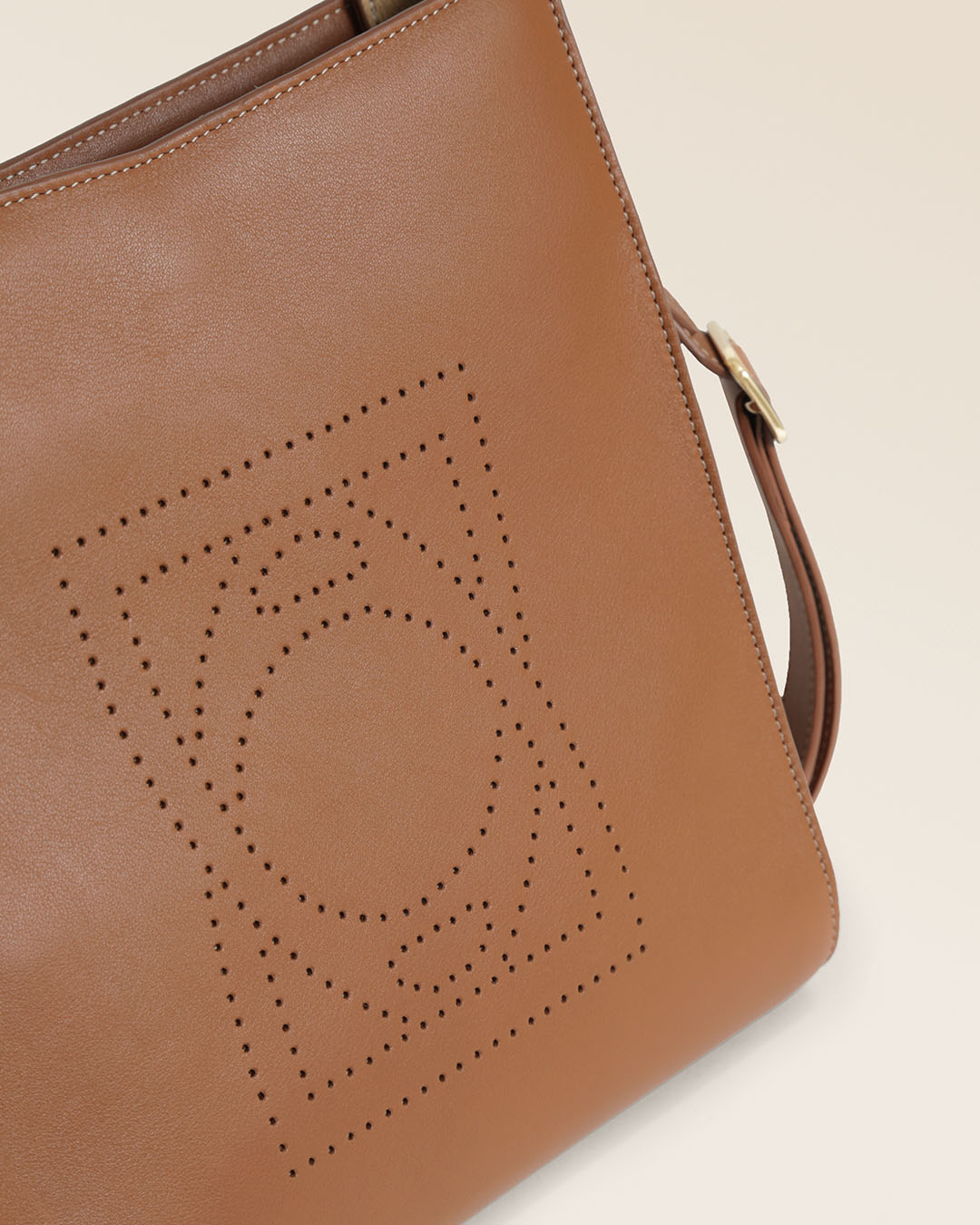 Le sac Mini Étrivière Renouard en cuir lisse camel et bandoulière cuir, vu de près en studio.