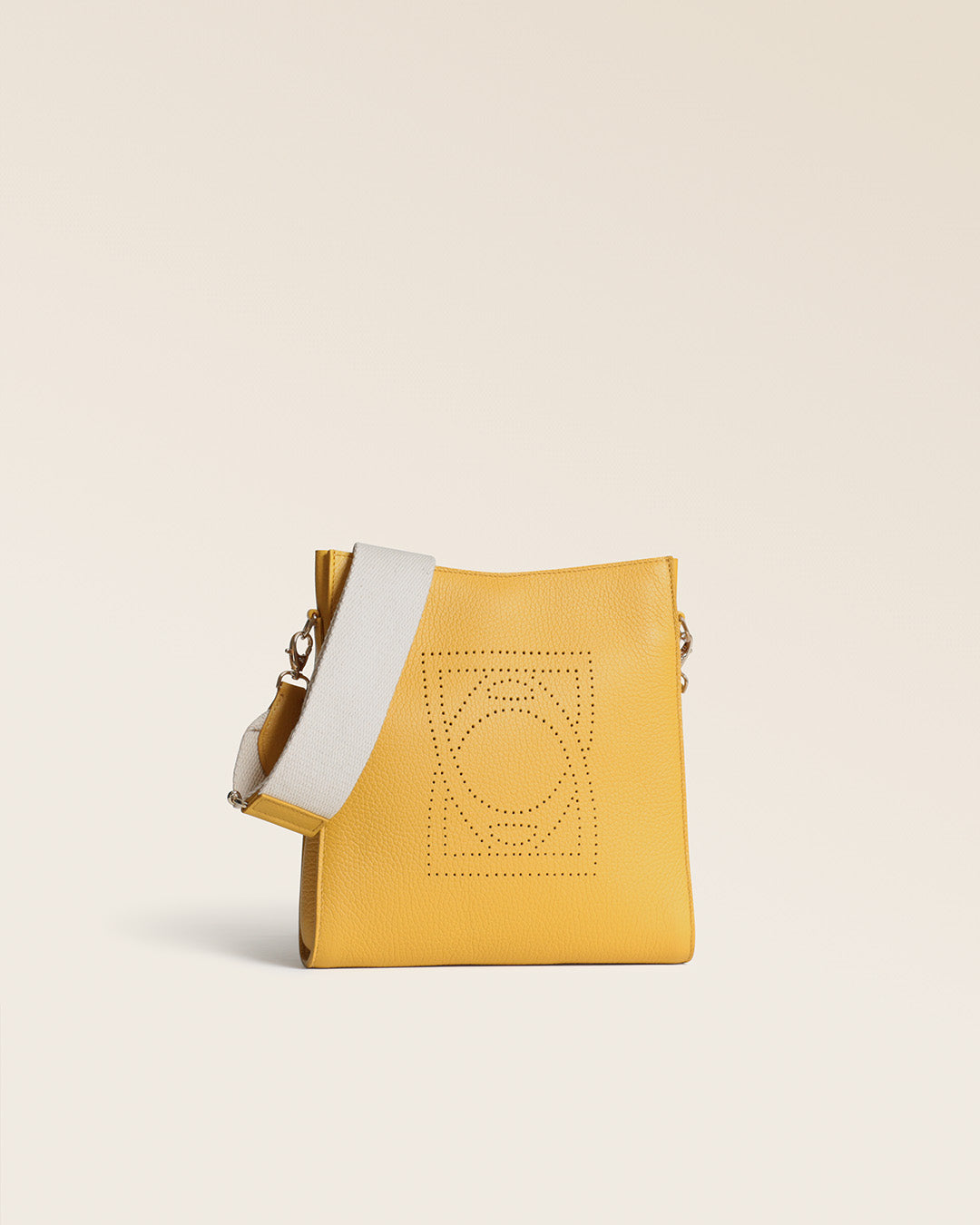 Le sac mini Étrivière Renouard en cuir vigogne ananas et sa bandoulière en craie, vu de quart en studio.