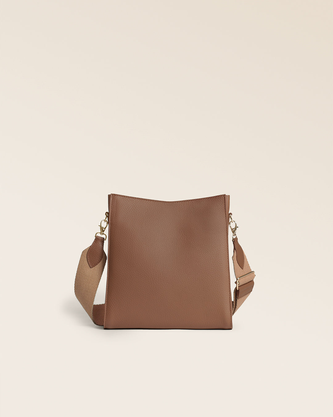 Le sac Mini Étrivière Renouard en cuir façon vigogne fauve et sa bandoulière coton camel, vu de dos en studio.