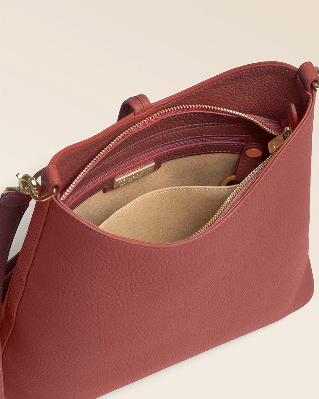 Notre sac Petit Cob Renouard en cuir façon vigogne terracotta et bandoulière cuir, vu de l'intérieur en studio.