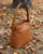 Le sac Rosa Grand modèle Renouard en cuir lisse camel, vu de quart en ambiance.
