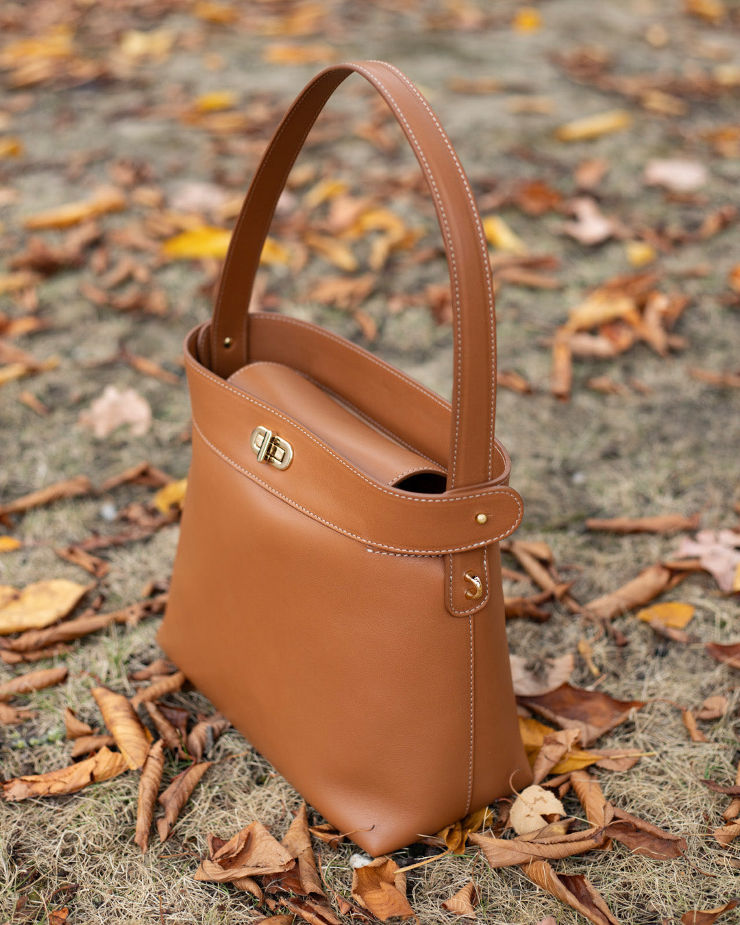 Le sac Rosa Grand modèle Renouard en cuir lisse camel, vu de quart en ambiance.