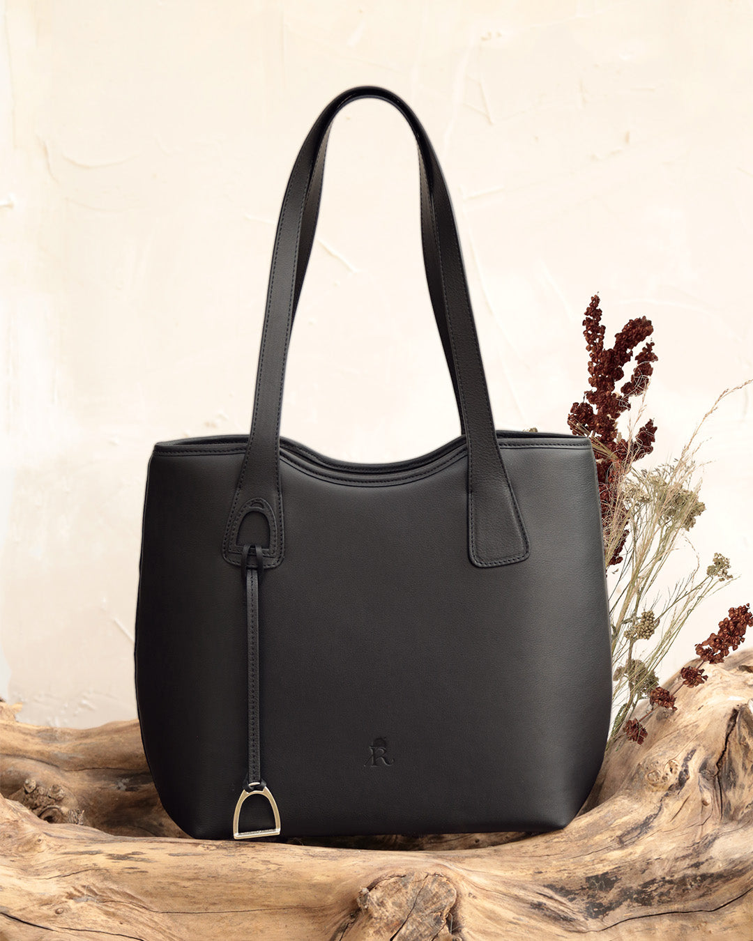 Le sac Soline Renouard en cuir lisse noir et son bijou étrier doré pâle, vu de face en ambiance.