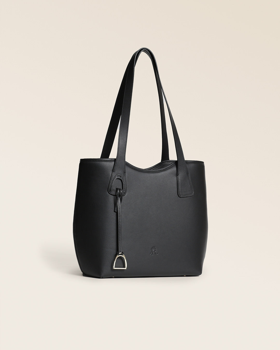 Le sac Soline Renouard en cuir lisse noir et son bijou étrier doré pâle, vu de quart en studio.