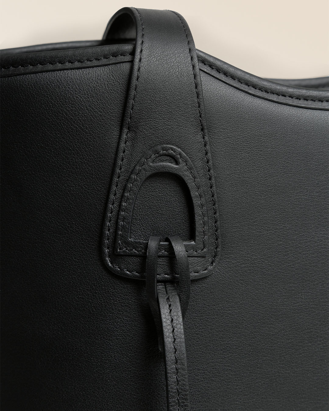 Le sac Soline Renouard en cuir lisse noir et son bijou étrier doré pâle, vu en détails en studio.