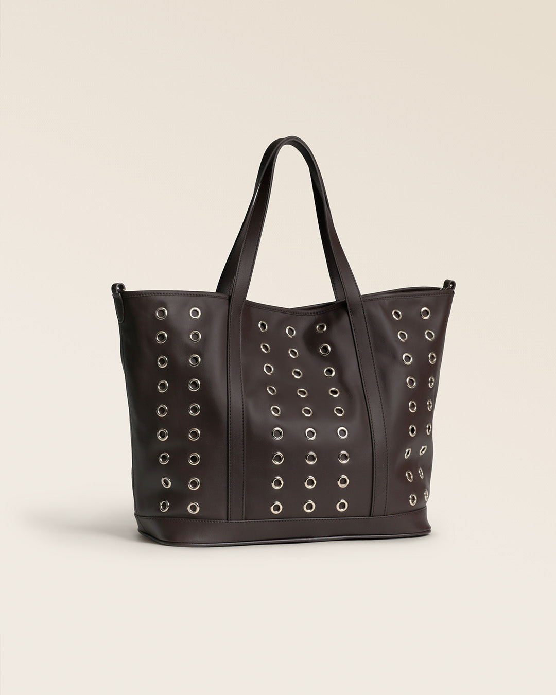 Le sac Zanzibar Renouard en cuir lisse ébène et ses oeillets dorés, vu de quart en studio.