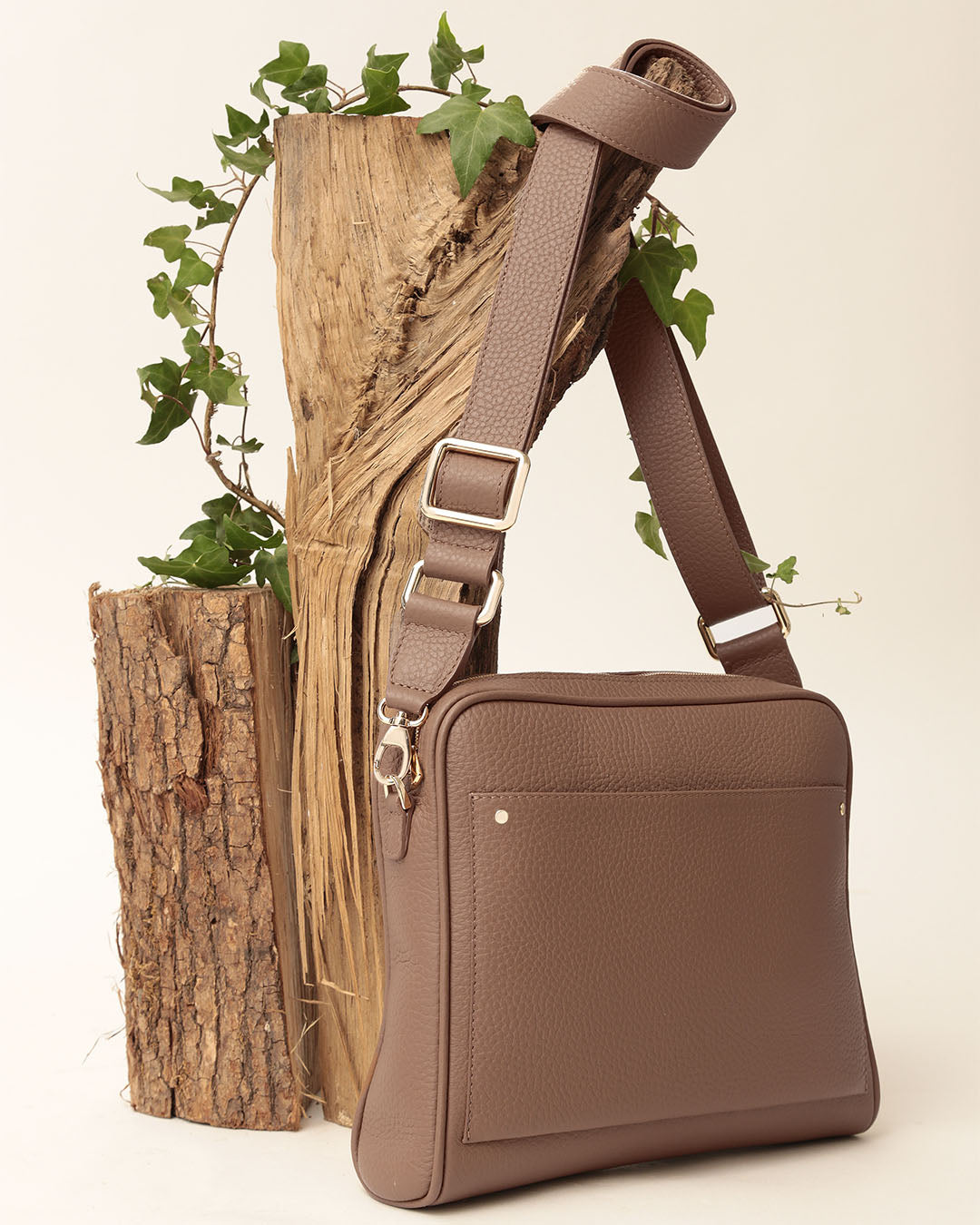 Le sac Zoom Renouard en cuir façon vigogne fauve et sa bandoulière cuir assortie, vu de quart en ambiance.