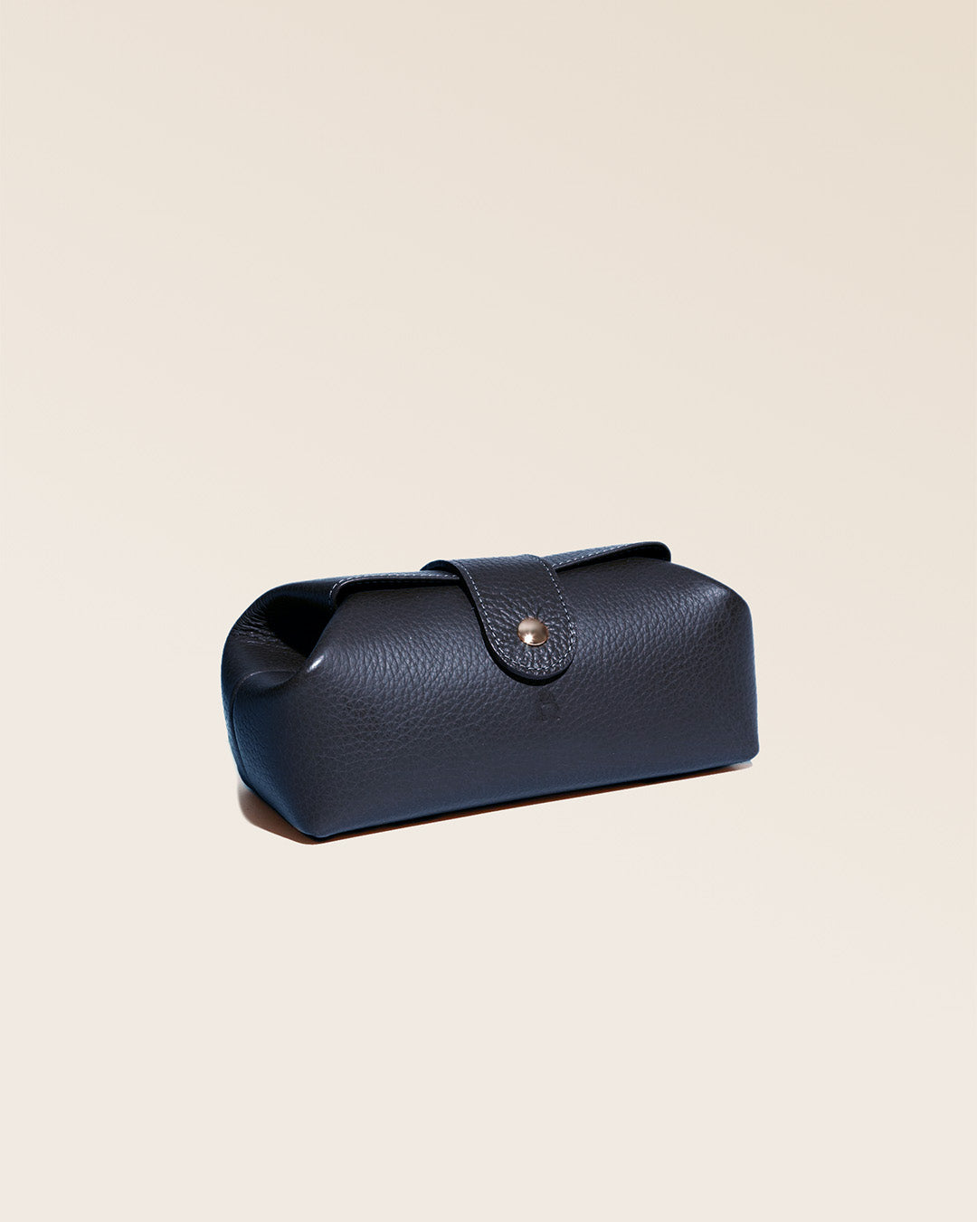 Notre trousse Vecchio Renouard en cuir façon vigogne bleu marine vue de quart en studio.