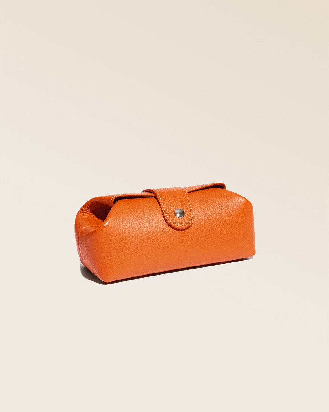 Notre trousse Vecchio Renouard en cuir façon vigogne orange vue de quart en studio.