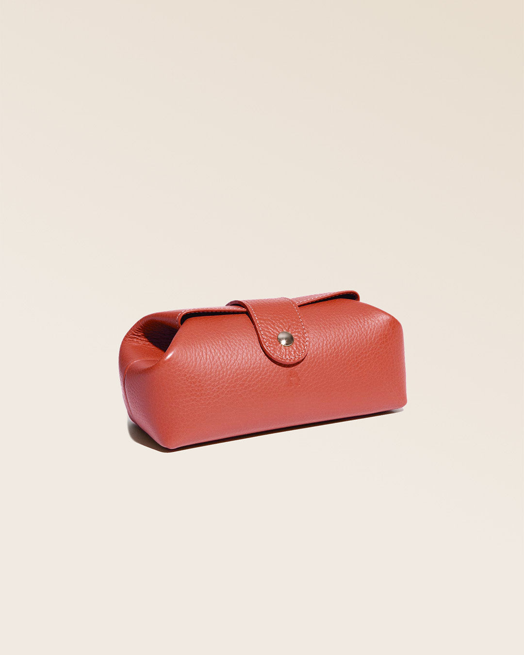 Notre trousse Vecchio Renouard en cuir façon vigogne terracotta vue de quart en studio.