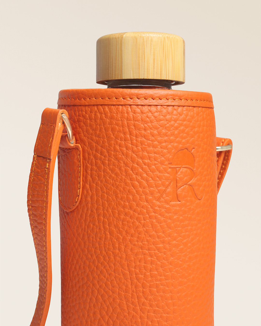 Notre étui pour bouteille d'eau ou gourde en cuir façon vigogne orange, vu de près en studio